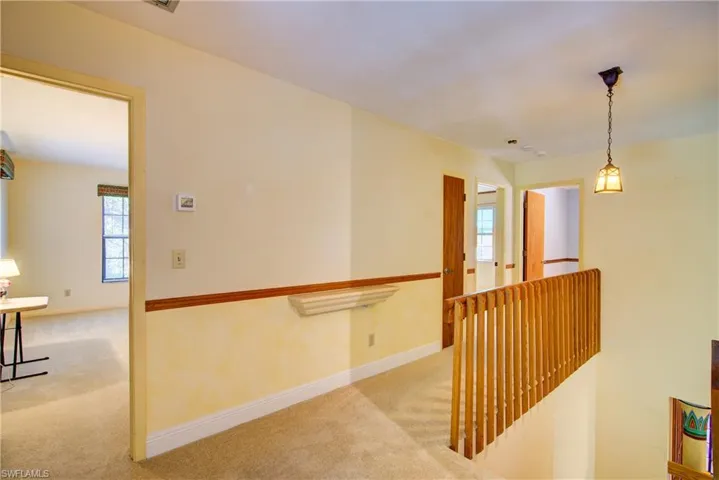 Hall with carpet floors and an upstairs landing