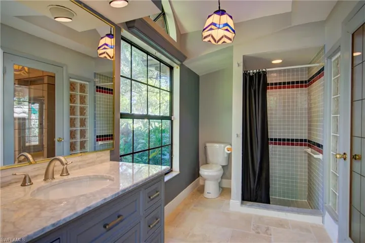 Full bath featuring a shower stall, vanity, and light stone finish floors