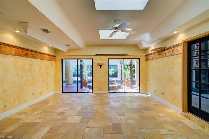 Empty room with recessed lighting, a skylight, stone tile floors, and a ceiling fan