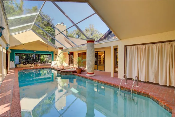 Outdoor pool with a patio, glass enclosure, and a sunroom