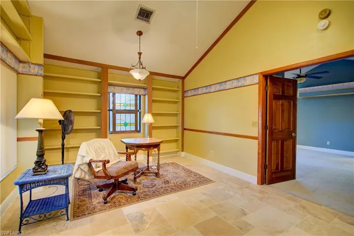 Sitting room with built in shelves, lofted ceiling, and a ceiling fan