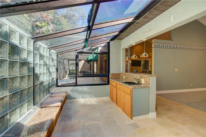 Unfurnished sunroom with exterior kitchen, a skylight, and a patio area