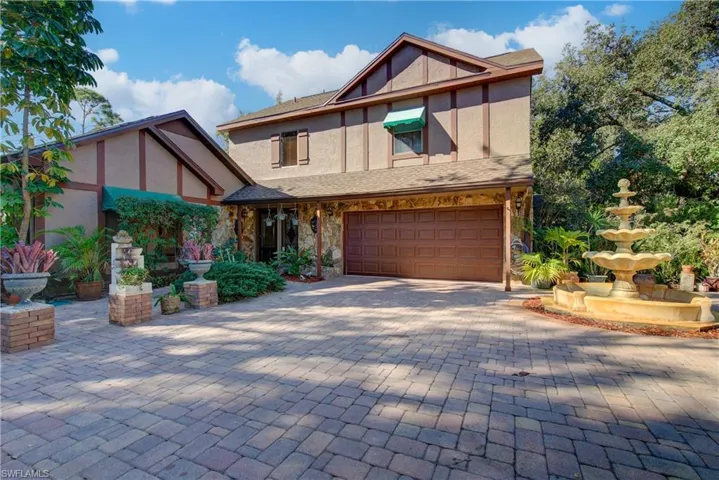 Tudor house with a garage, stucco siding, decorative driveway, and stone siding