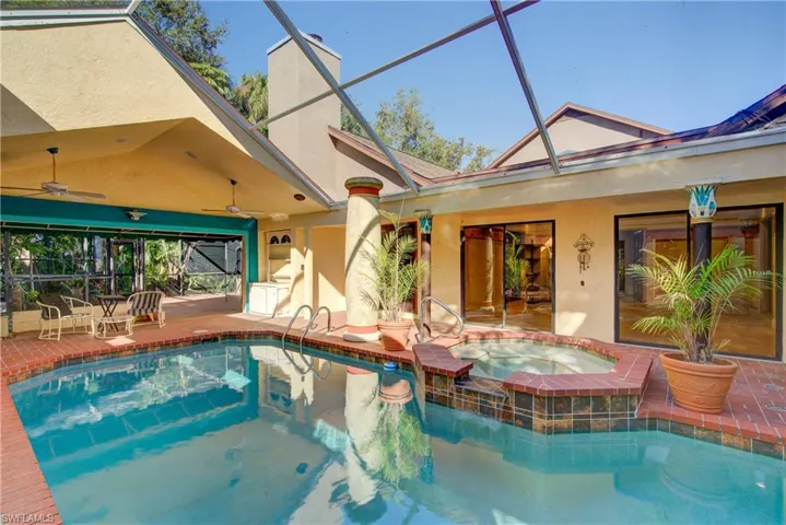View of swimming pool featuring glass enclosure, a patio, a sunroom, and a pool with connected hot tub