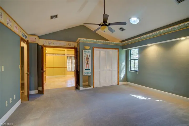 Unfurnished bedroom featuring carpet floors, a closet, vaulted ceiling, and a ceiling fan