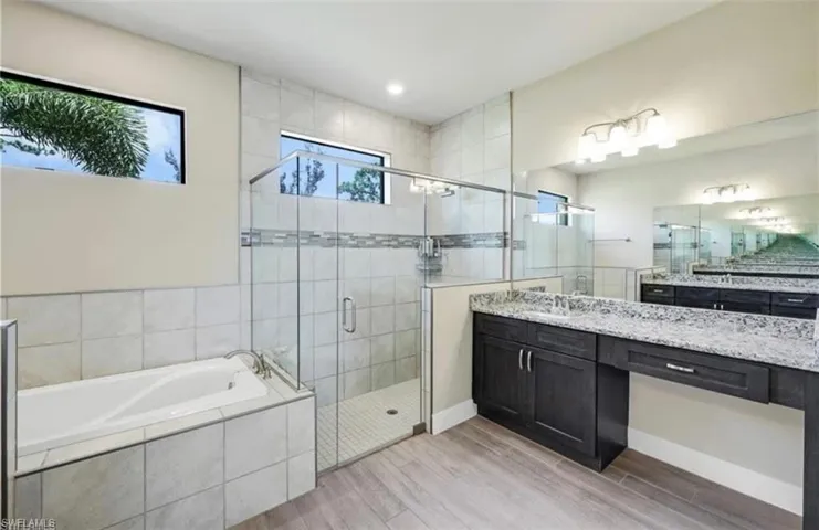 Bathroom featuring vanity, a garden tub, a stall shower, light wood-type flooring, and recessed lighting