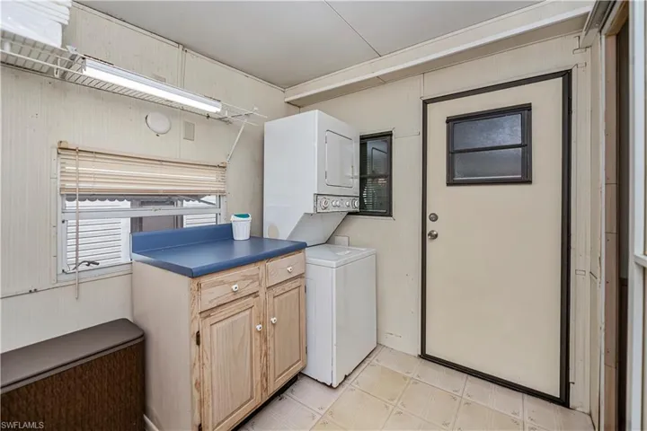 Washroom with stacked washer / dryer, cabinet space, and light floors