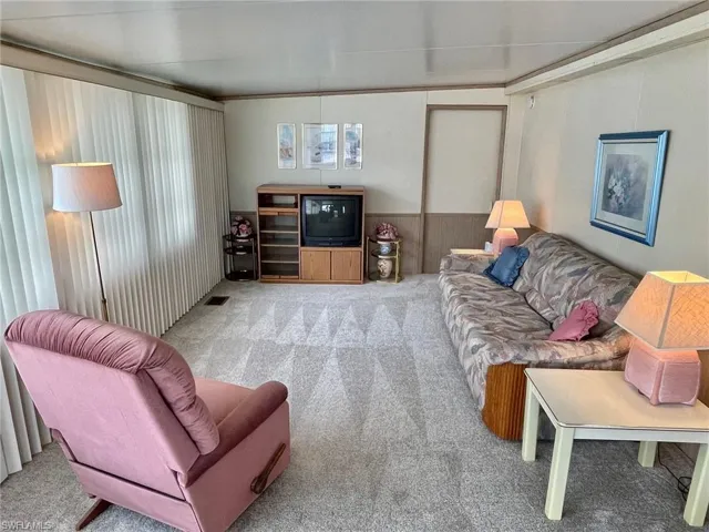 Living area featuring carpet floors, a wainscoted wall, and wooden walls