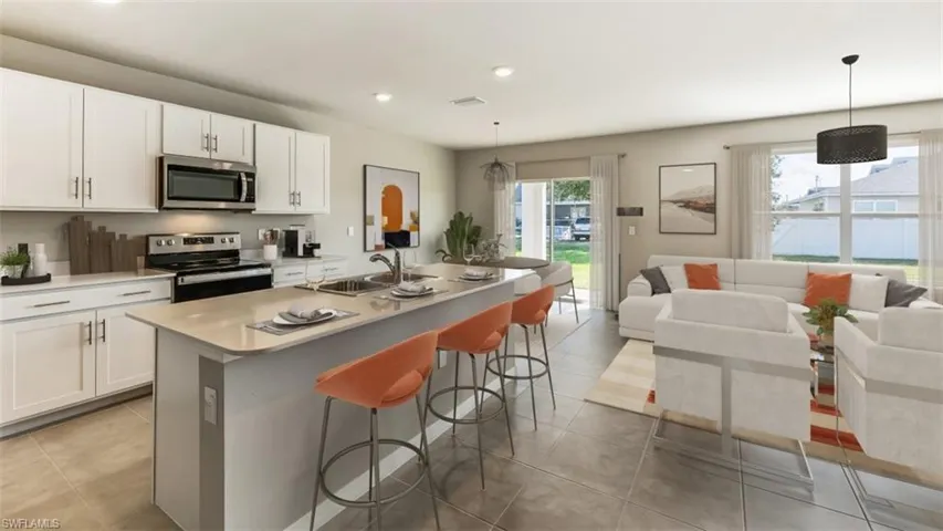 Kitchen featuring stainless steel appliances, an island with sink, open floor plan, white cabinets, and pendant lighting