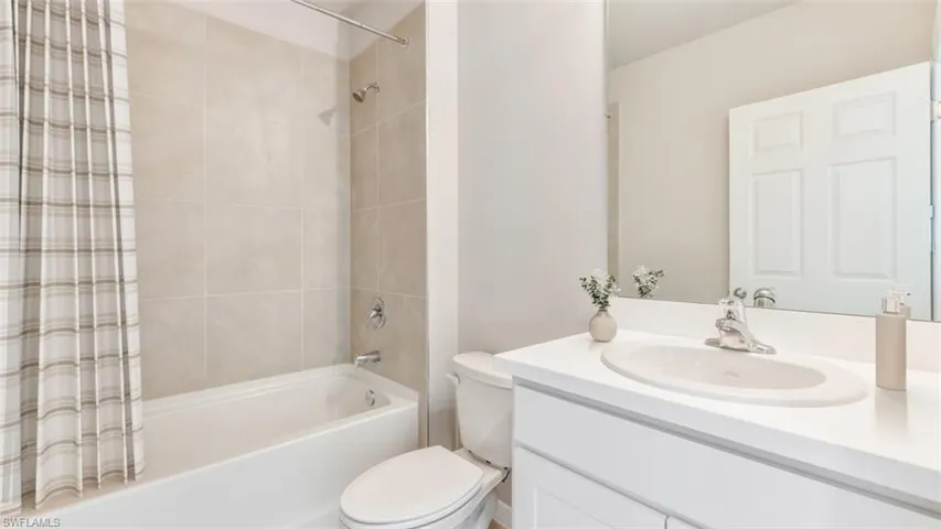 Bathroom featuring vanity and shower / bathtub combination with curtain