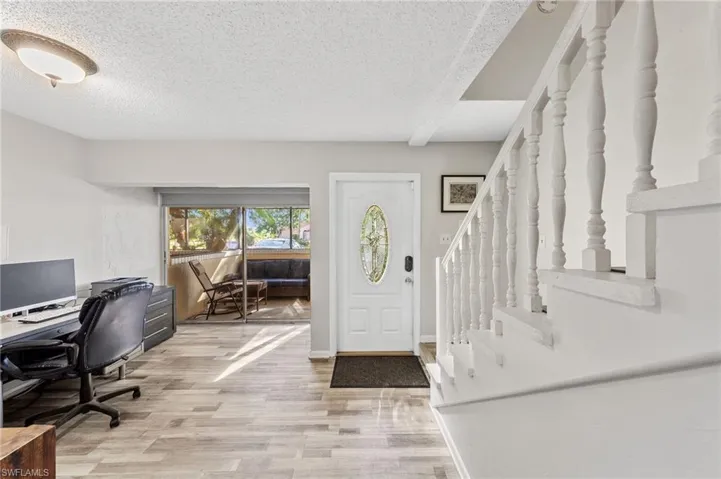 Foyer with stairway, light wood-style floors, and a textured ceiling