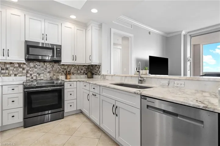 Kitchen with tasteful backsplash, white cabinetry, sink, ornamental molding, and stainless steel appliances