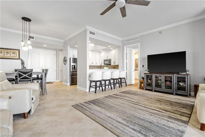 Tiled living room featuring ornamental molding and ceiling fan
