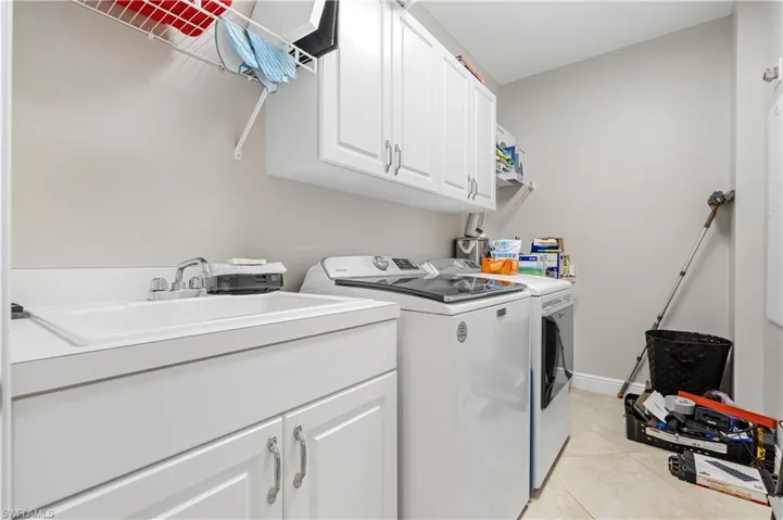 Washroom with New washer and dryer, sink, cabinets, and light tile patterned flooring