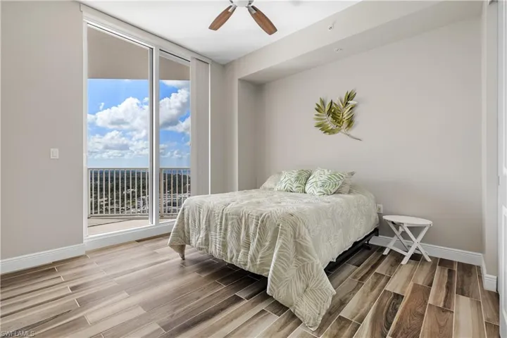 Bedroom 2 with ceiling fan, access to exterior, and a wall of windows