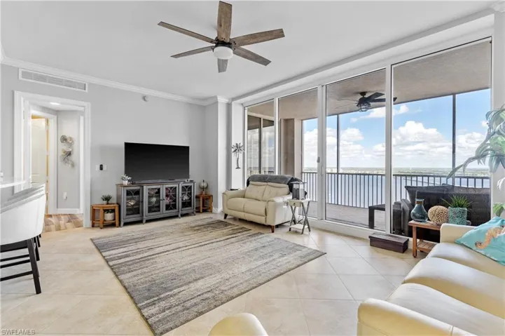 Living room with light tile patterned floors, ornamental molding, and ceiling fan