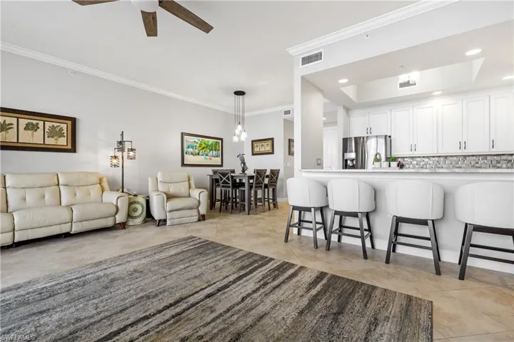 Tiled living room with ceiling fan and ornamental molding