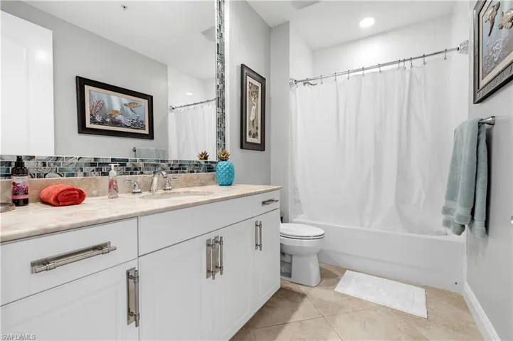 Full bathroom featuring tile patterned floors, toilet, tasteful backsplash, vanity, and shower / bath combo with shower curtain