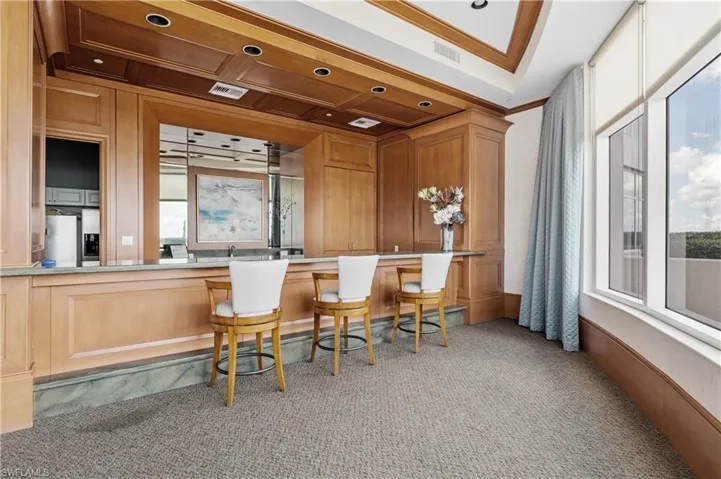 Community Room Bar area featuring crown molding, light colored carpet, and stainless steel fridge