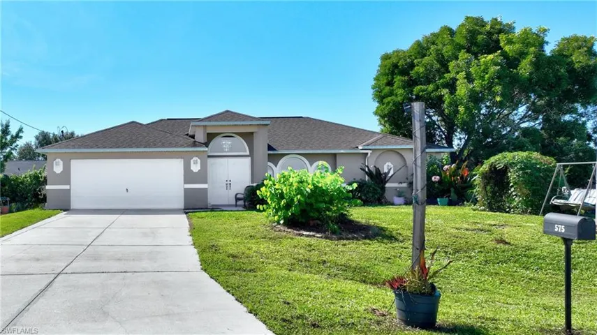 Ranch-style house featuring stucco siding, driveway, a front yard, a garage, and a shingled roof