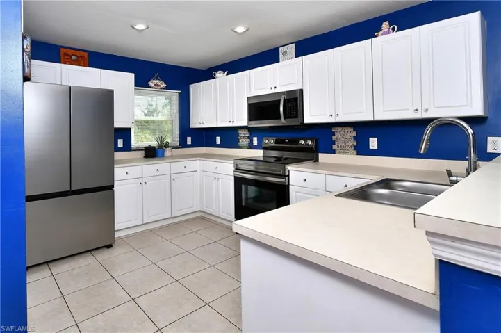 Kitchen with stainless steel appliances, white cabinetry, light countertops, light tile patterned floors, and recessed lighting