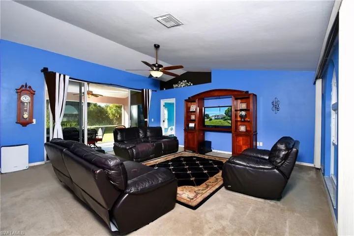 Carpeted living area with vaulted ceiling, a ceiling fan, and arched walkways