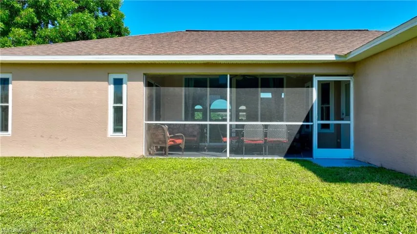 Back of house featuring stucco siding, a yard, roof with shingles, and a sunroom