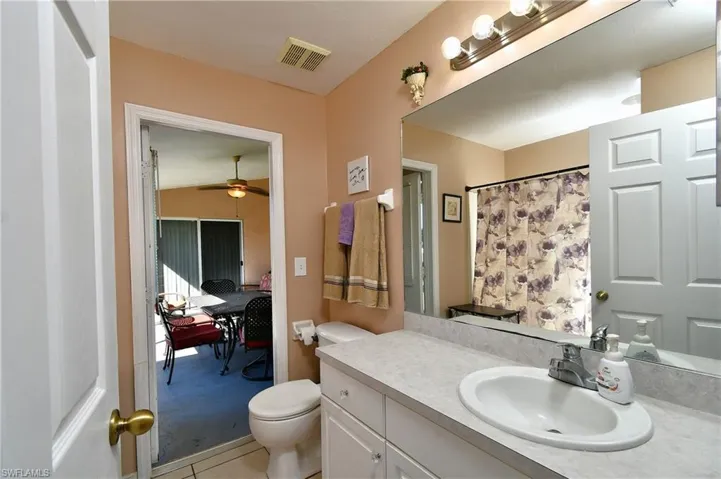 Full bath featuring vanity, light tile patterned floors, a ceiling fan, and a shower with shower curtain