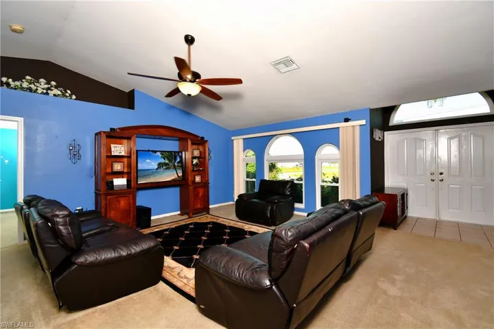 Living area with carpet flooring, lofted ceiling, ceiling fan, and tile patterned floors