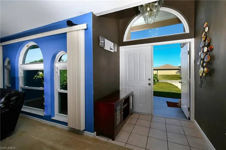 Entryway featuring light tile patterned flooring, healthy amount of natural light, and a chandelier