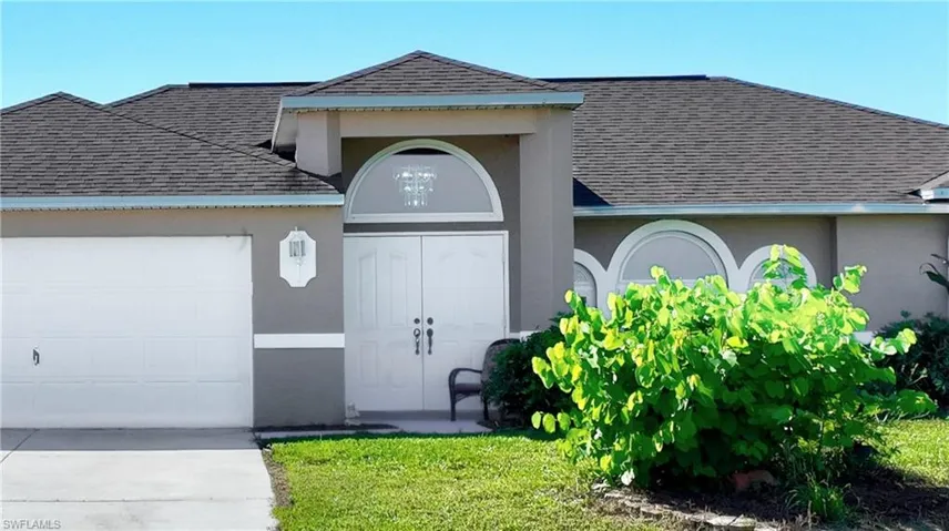 Doorway to property with roof with shingles, an attached garage, stucco siding, and concrete driveway