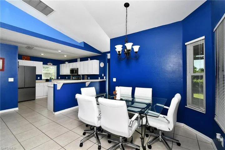 Dining space with vaulted ceiling, light tile patterned floors, and a chandelier