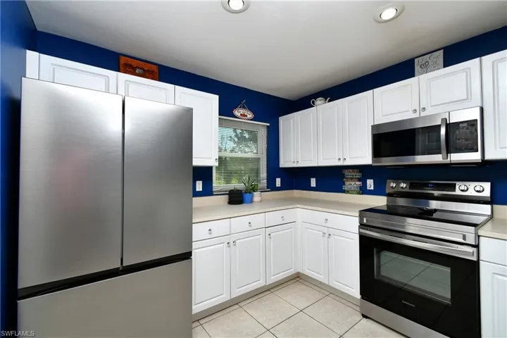 Kitchen featuring appliances with stainless steel finishes, light countertops, white cabinets, light tile patterned floors, and recessed lighting