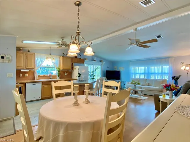 DINING ROOM featuring ceiling fan with notable chandelier, light wood-style flooring and vaulted ceiling