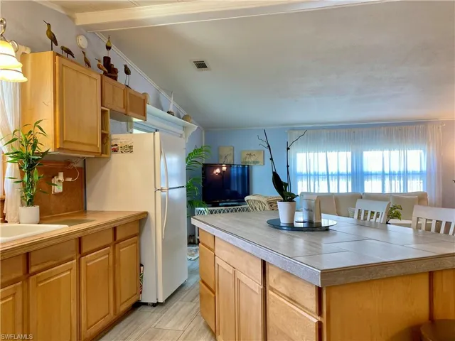 KITCHEN featuring vaulted ceiling, white refrigerator and light flooring