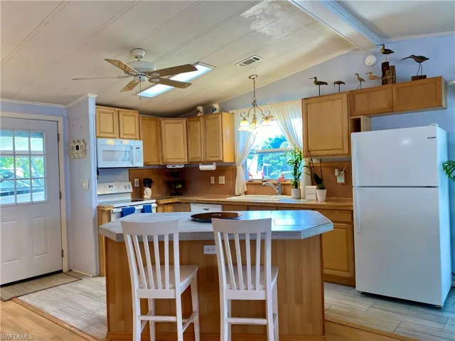 KITCHEN featuring tasteful backsplash, center island, sink, vaulted ceiling and white appliances