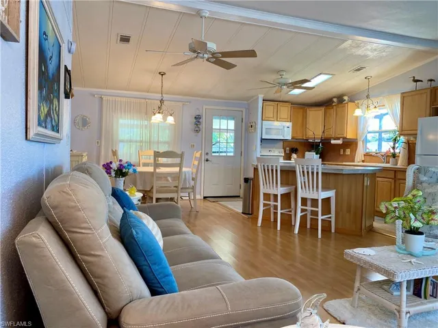 LIVING ROOM featuring a healthy amount of sunlight, light wood-style floors, vaulted ceiling and ceiling fan