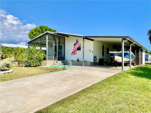 FRONT of property with a sunroom, a front lawn, and a carport