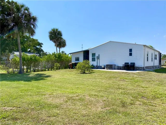 Rear view of house with a lawn and a patio
