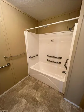 Bathroom featuring tile flooring, shower / bathing tub combination, and a textured ceiling
