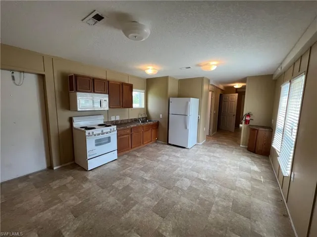 Kitchen with white appliances, light tile flooring, and plenty of natural light