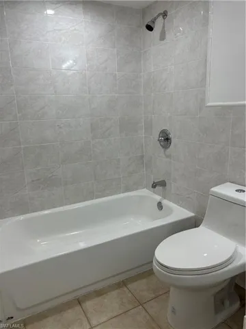 Bathroom with shower / bath combination, light tile patterned floors, and tile walls