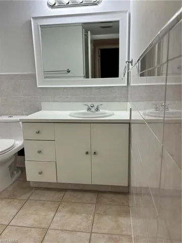 Half bath with vanity, tile walls, and light tile patterned floors