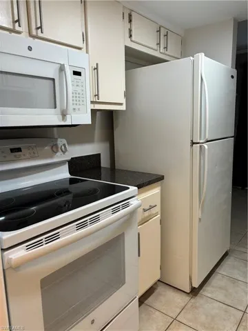 Kitchen featuring white appliances, white cabinetry, and light tile patterned flooring