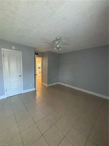 Spare room featuring light tile patterned flooring, a ceiling fan, and a textured ceiling