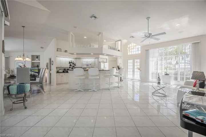 Living area featuring a high ceiling, light tile patterned flooring, french doors, a ceiling fan, and hanging lights