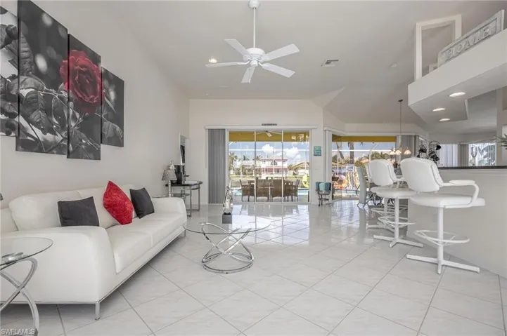 Living room with ceiling fan, recessed lighting, light tile patterned flooring, and vaulted ceiling