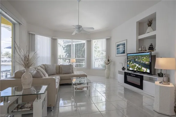 Living area featuring a ceiling fan, light tile patterned flooring, and built in shelves