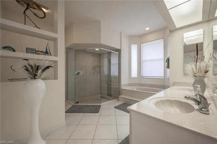 Bathroom with a bath, a shower stall, light tile patterned flooring, and double vanity