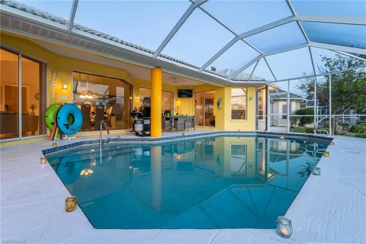Swimming pool with a sunroom, glass enclosure, a patio, and outdoor dining area